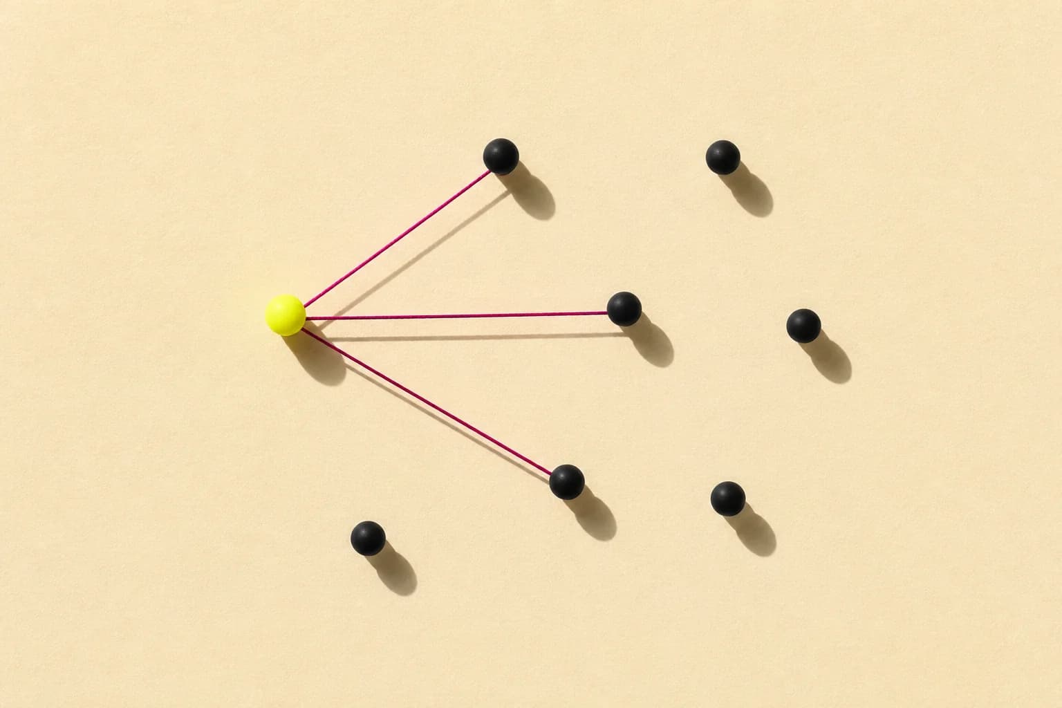 Black pins on a cream felt board, three of them connected by magenta thread to a larger yellow pin.