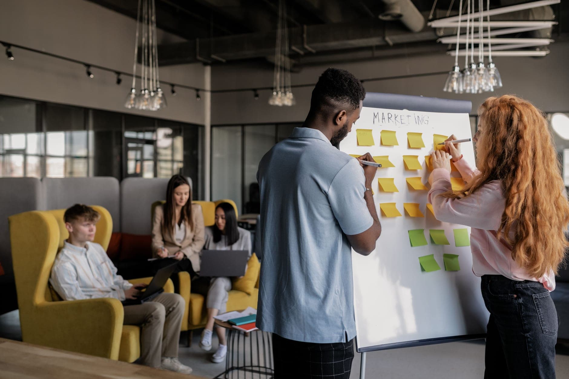 A team planning a marketing campaign with sticky notes on a whiteboard.